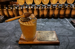 Cocktail topped with a honey stirrer dripping in honey, and chocolate in the shape of a bee and honeycomb